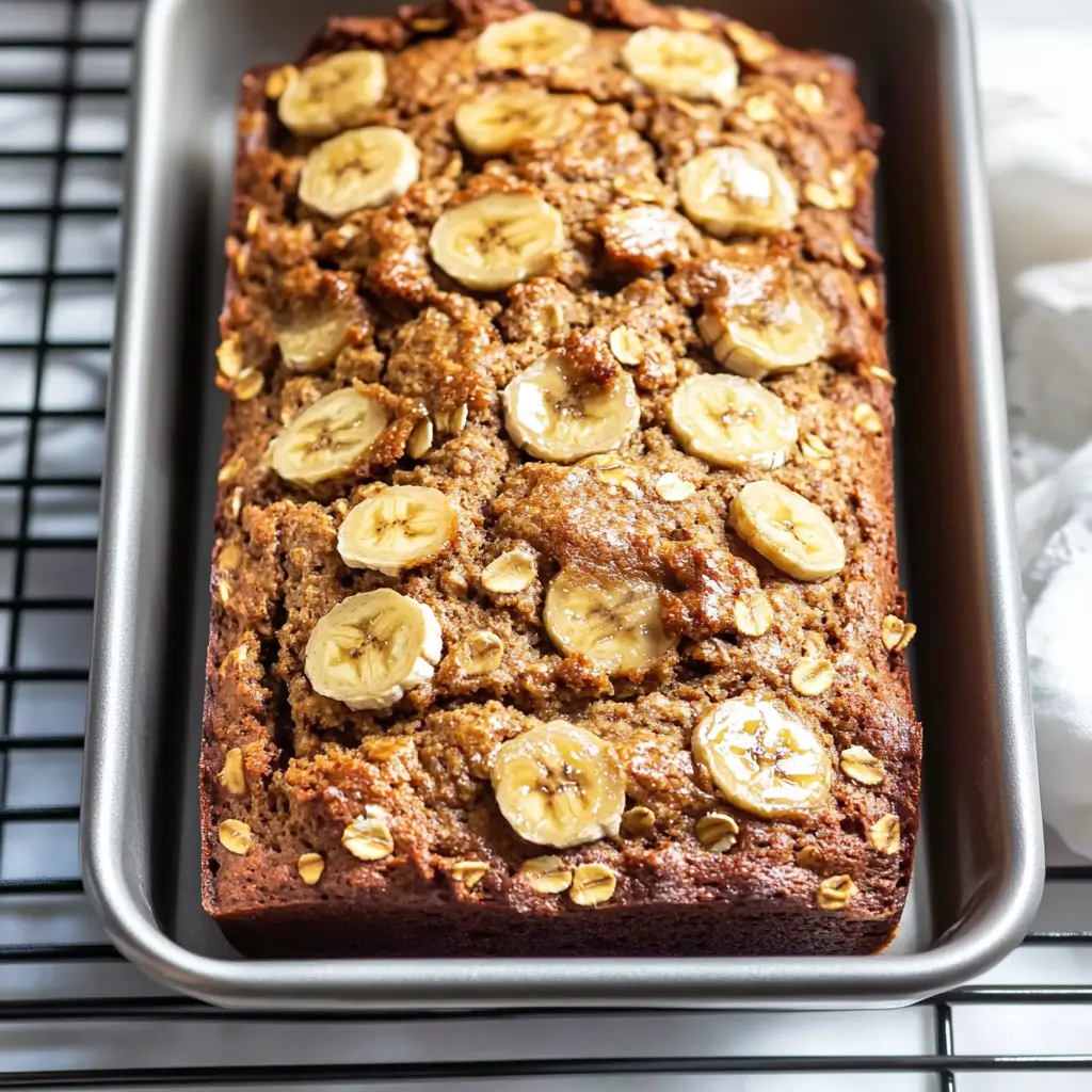 Healthy Oatmeal Banana Bread You’ll Want Every Morning 2 Healthy oatmeal banana bread topped with banana slices and oats in a baking pan